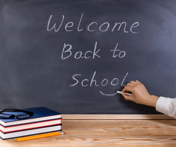 Teacher placing smile symbol on welcome back to school message w