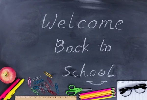 Back to school message with student supplies on chalkboard