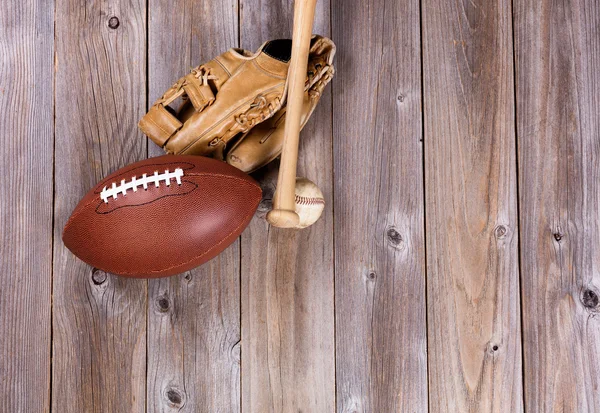 Football and baseball equipment on rustic wooden boards
