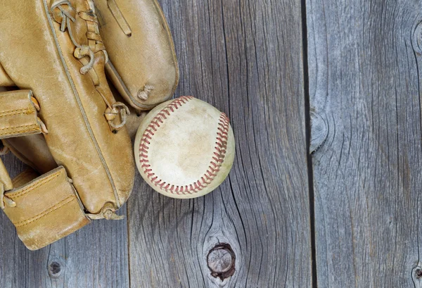 Used Baseball and Worn Glove on old wood