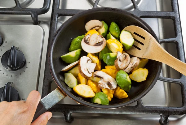 Stirring vegetables in Frying Pan with wooden spoon