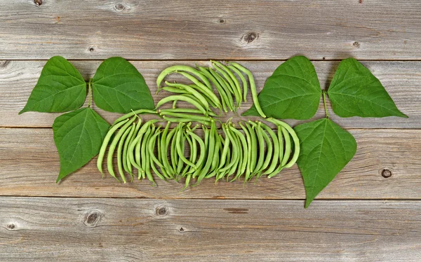Organized green beans and leaves on rustic wooden boards