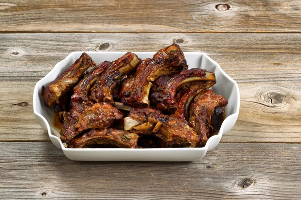 BBQ pork ribs in large plate on rustic wooden boards