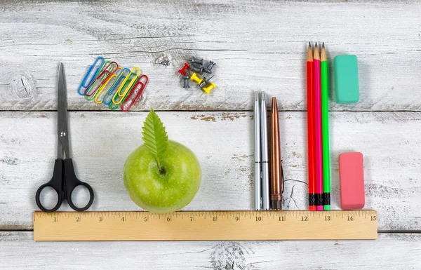 School supplies in line with ruler on white desktop