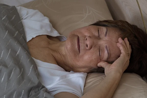 Senior woman having difficulty falling asleep at nighttime