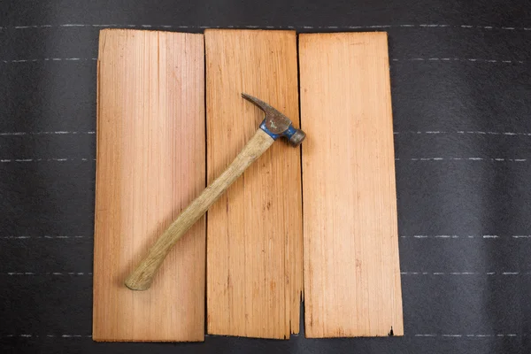 Used roofing hammer with new cedar wood shingles on felt paper