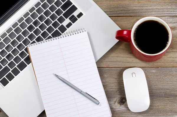 Blank notebook and pen with laptop on office desktop