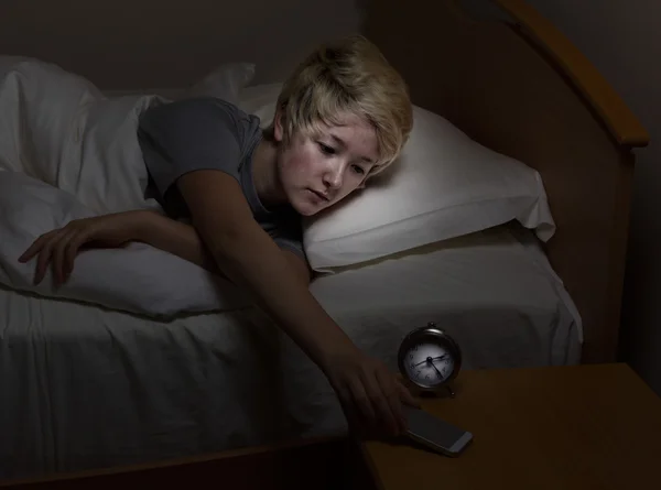 Teen girl checking cell phone late at night while in bed