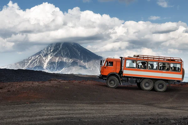 Expedition truck on mountain road on background volcanoes
