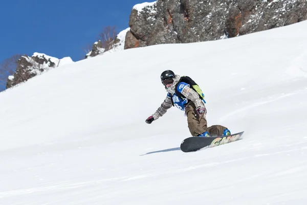 Girl snowboarder rides steep mountains. Kamchatka, Far East, Russia