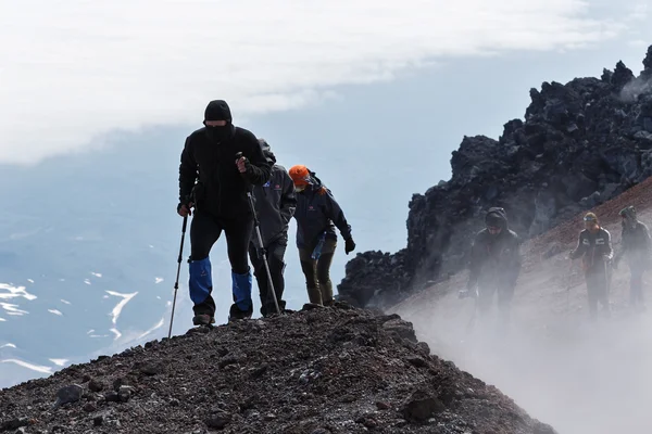 Group of tourists climbing to top crater of active volcano