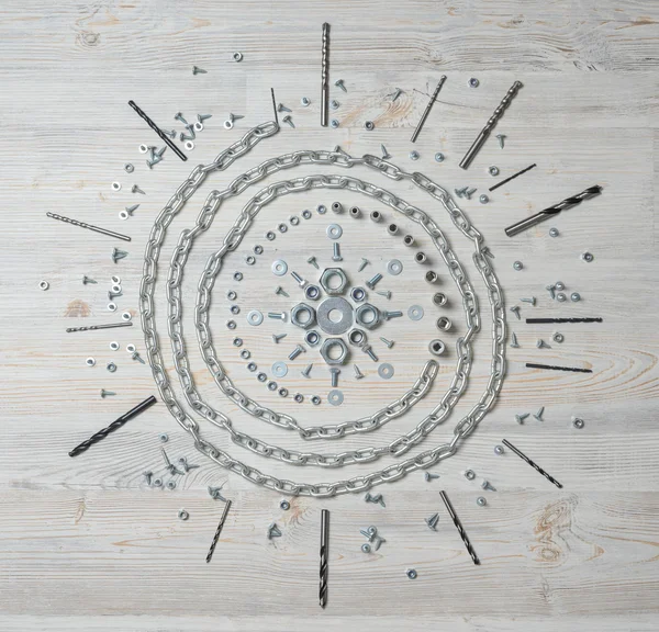Chain, bolts and nuts on white wooden bench in the form of mandala