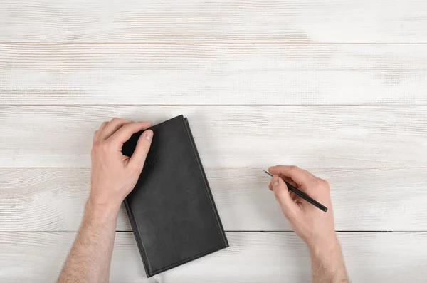 Closeup hands of man holding pen and notebook