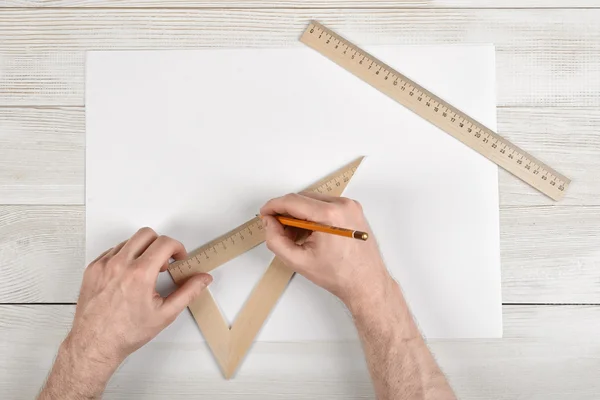 Work place of constructor with triangle centimeter ruler. Close-up man hands during measuring process.