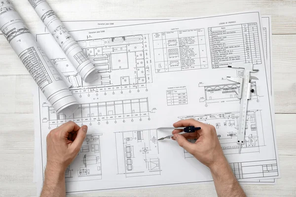Close-up hands of man holding an engineering divider over drawing plan in top view