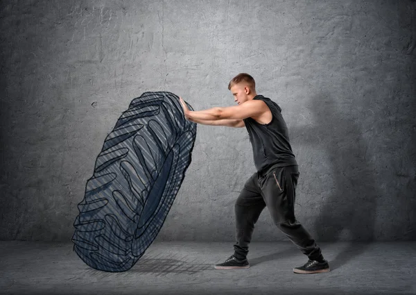 Side view of muscled young man pushing drawn tire to build strength