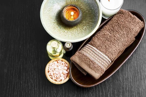 Spa setting with towel, candle, salt and body-oil