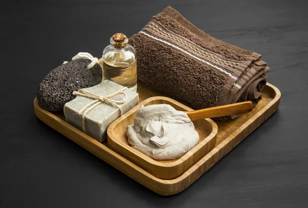 Skincare spa with clay mask,natural soap and oil in wooden tray