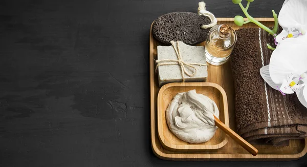 Skincare spa with clay mask,natural soap and oil in wooden tray