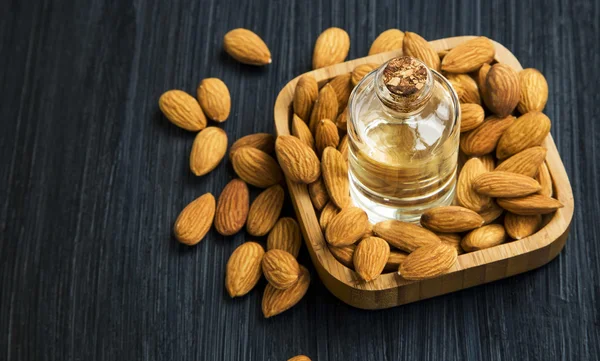Healthy almonds oil bottle with almonds nuts in wooden bowl