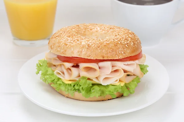 Bagel sandwich for breakfast with ham, orange juice and coffee