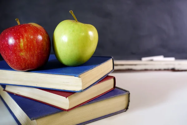 Red and green apples on school books