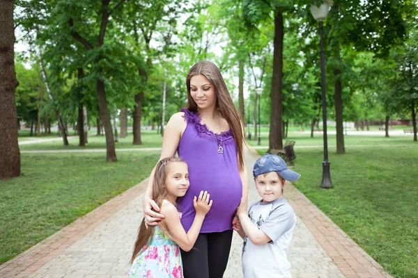 Pregnant woman with children in the park