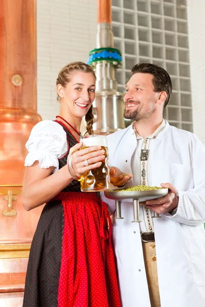 Brewer and woman with beer glass in brewery