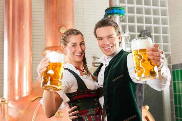 Man and woman with beer glass in brewery