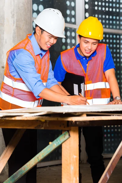 Asian architect and supervisor on building site