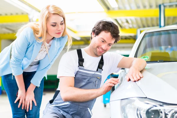 Customer and car painter in auto workshop