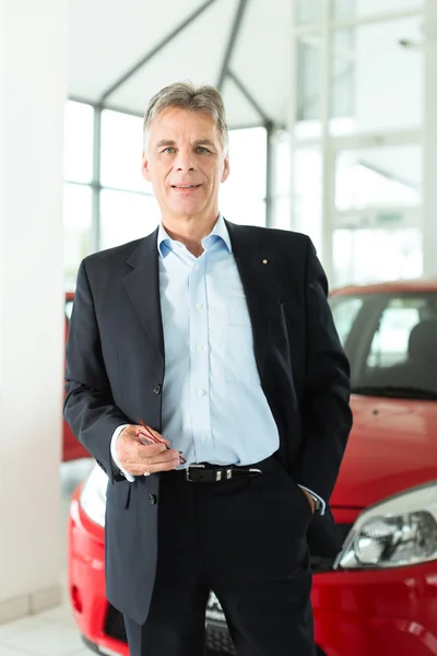 Mature man with auto in car dealership