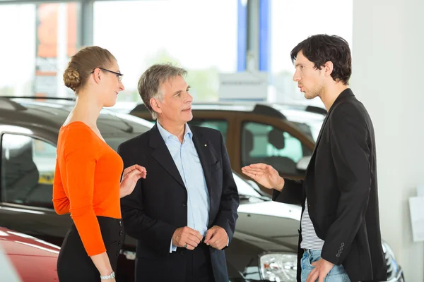 Man with couple and auto in car dealership