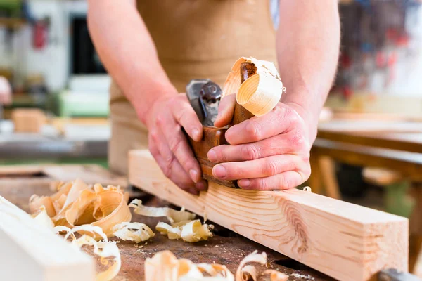 Carpenter with wood planer and workpiece in carpentry