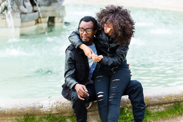 African couple in city sitting at fountain