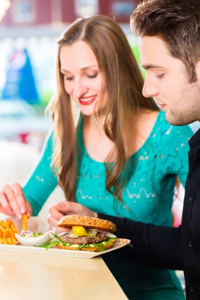 Couple eating fast food with burger and fries