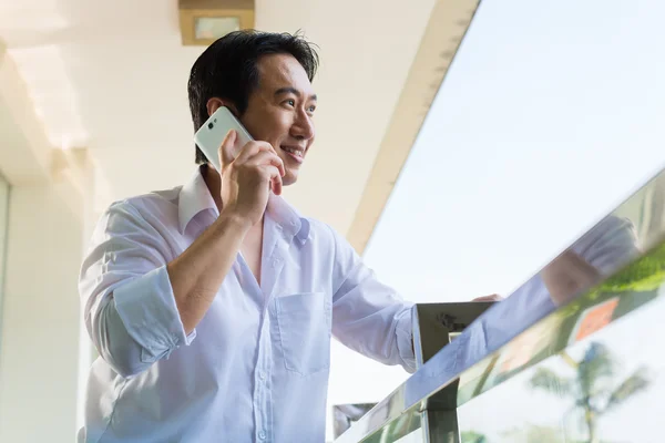 Asian man telephoning on balcony with mobile phone