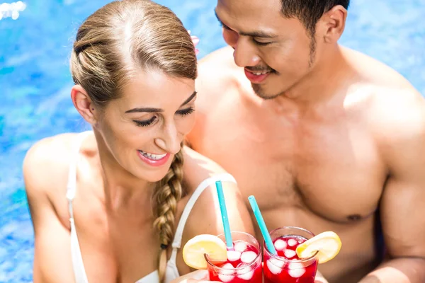 Couple in Asian hotel pool drinking cocktails