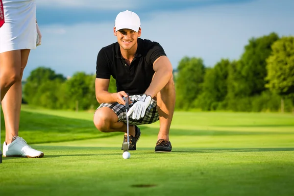 Young golf player on course putting and aiming