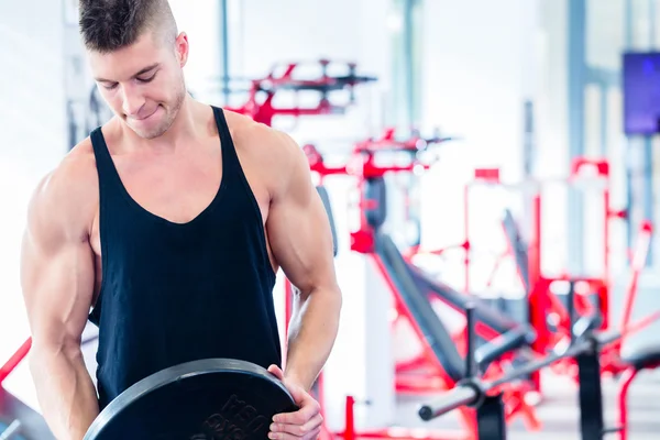 Man taking weights from stand in fitness gym