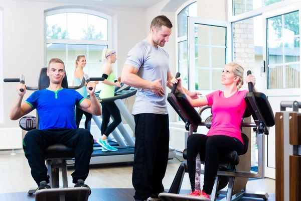 Woman with personal trainer doing sport in gym