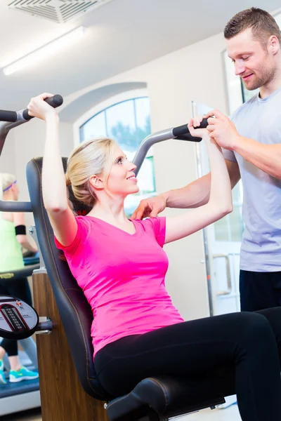 Woman with personal trainer doing sport in gym