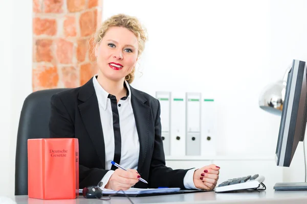 Lawyer in office with law book working on desk