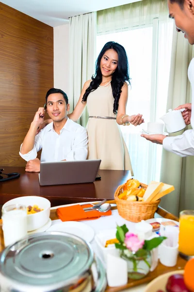 Asian room service waiter serving in hotel room