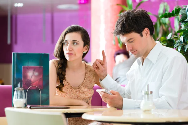 Couple in cafe not interacting but on phone