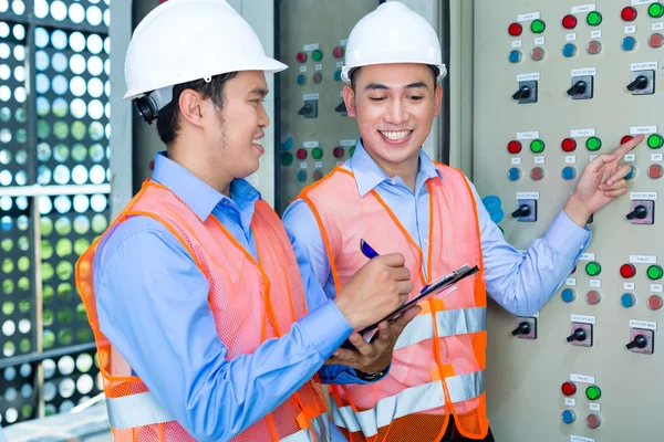 Asian technicians at panel on construction site