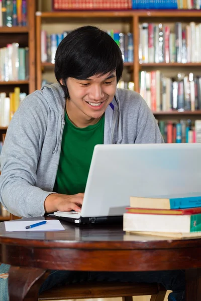 Asian man in library with laptop