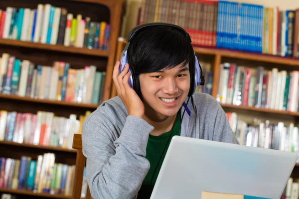 Man in library with laptop and headphones