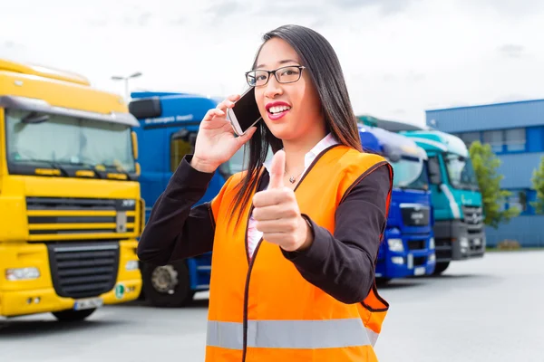 Female forwarder in front of trucks on a depot