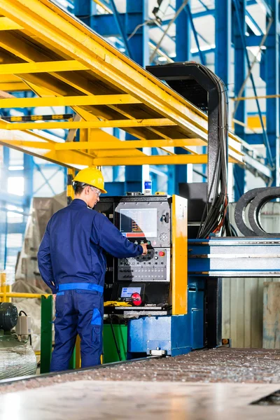 Worker in manufacturing plant at machine control panel